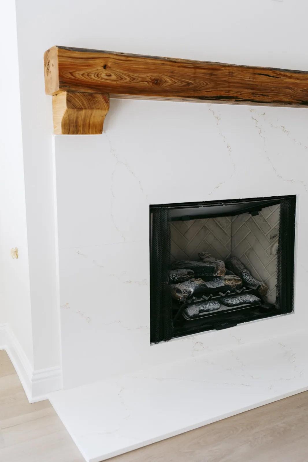 Fireplace with marble surround, live-edge cypress mantel, and hand-carved corbel