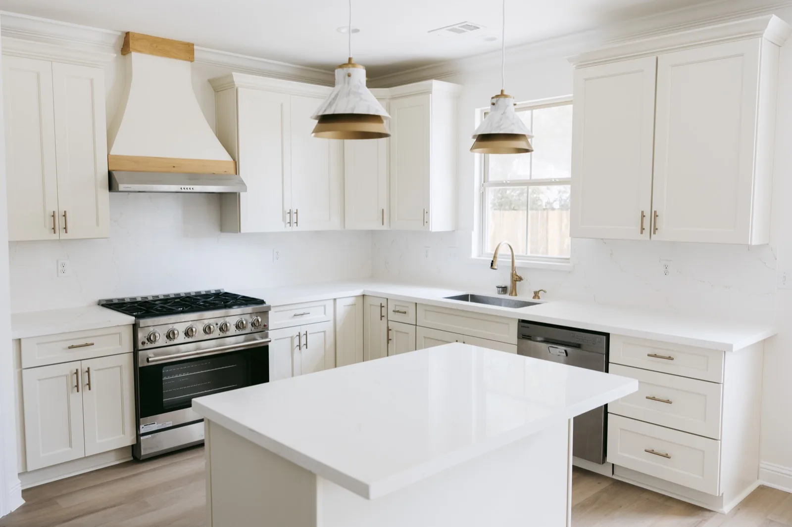 Kitchen from opposite angle — quartz countertops, brass hardware, professional gas range