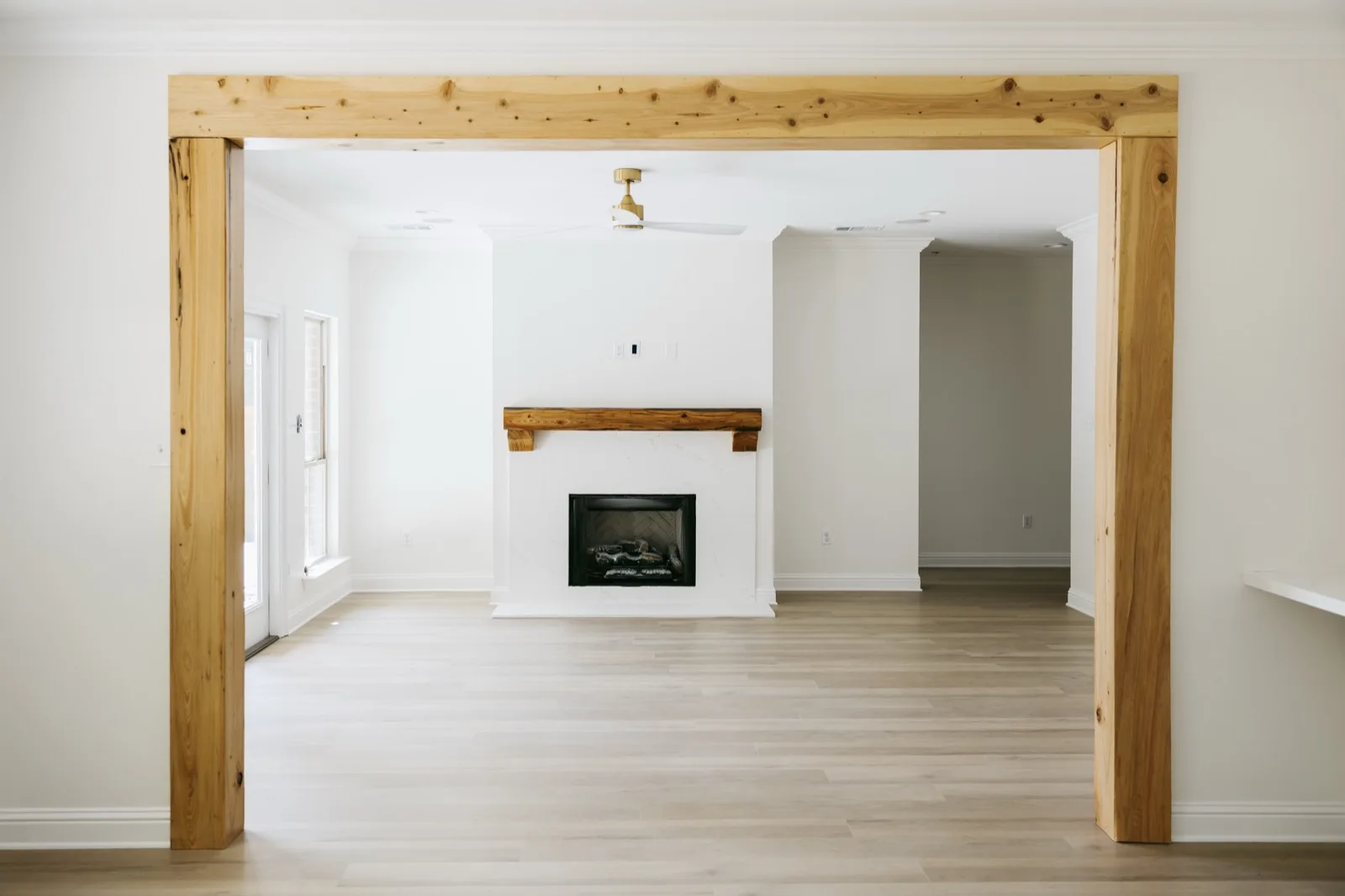 Mandeville luxury renovation — living room through cypress beam frame with fireplace
