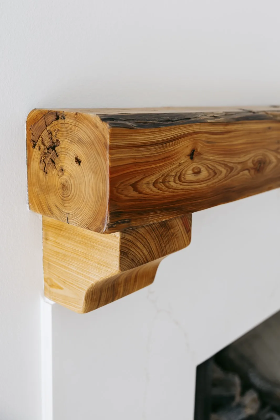 Live-edge cypress mantel — left side corbel with visible knot patterns and natural dark heartwood