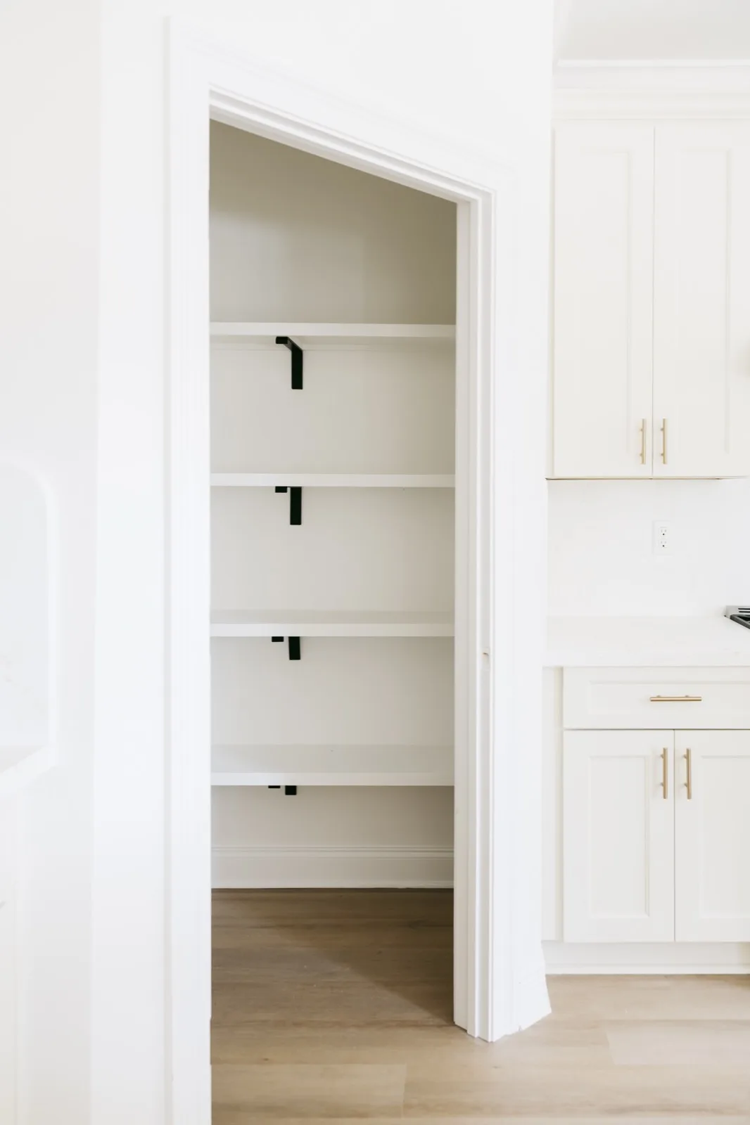 Walk-in pantry viewed from kitchen — built-in shelving with wrought iron brackets