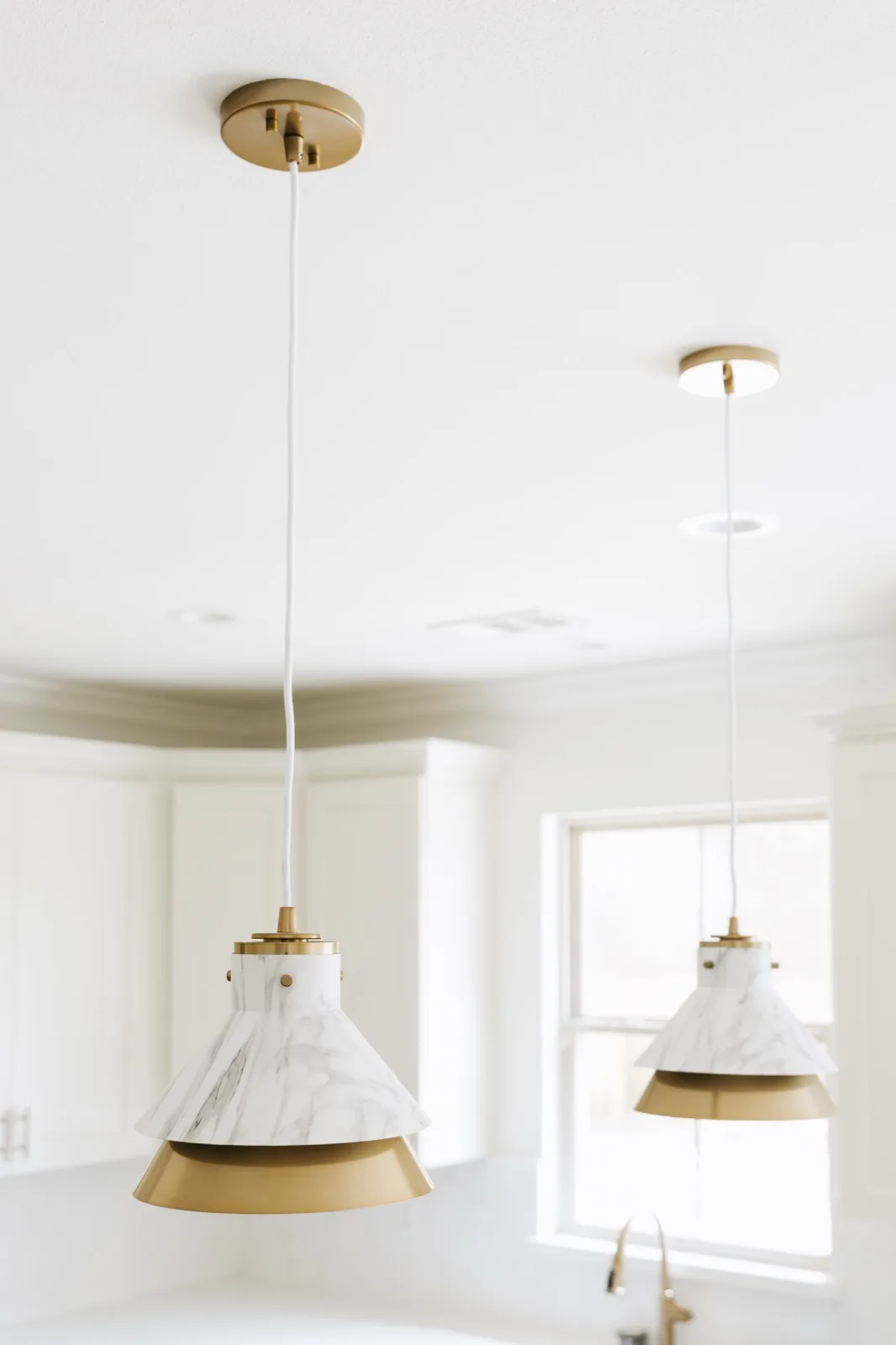 Marble-and-brass pendant lights — view from below showing natural stone grain