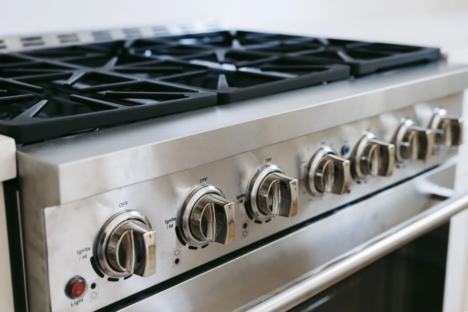 Professional gas range — stainless steel knob detail and cast iron grates