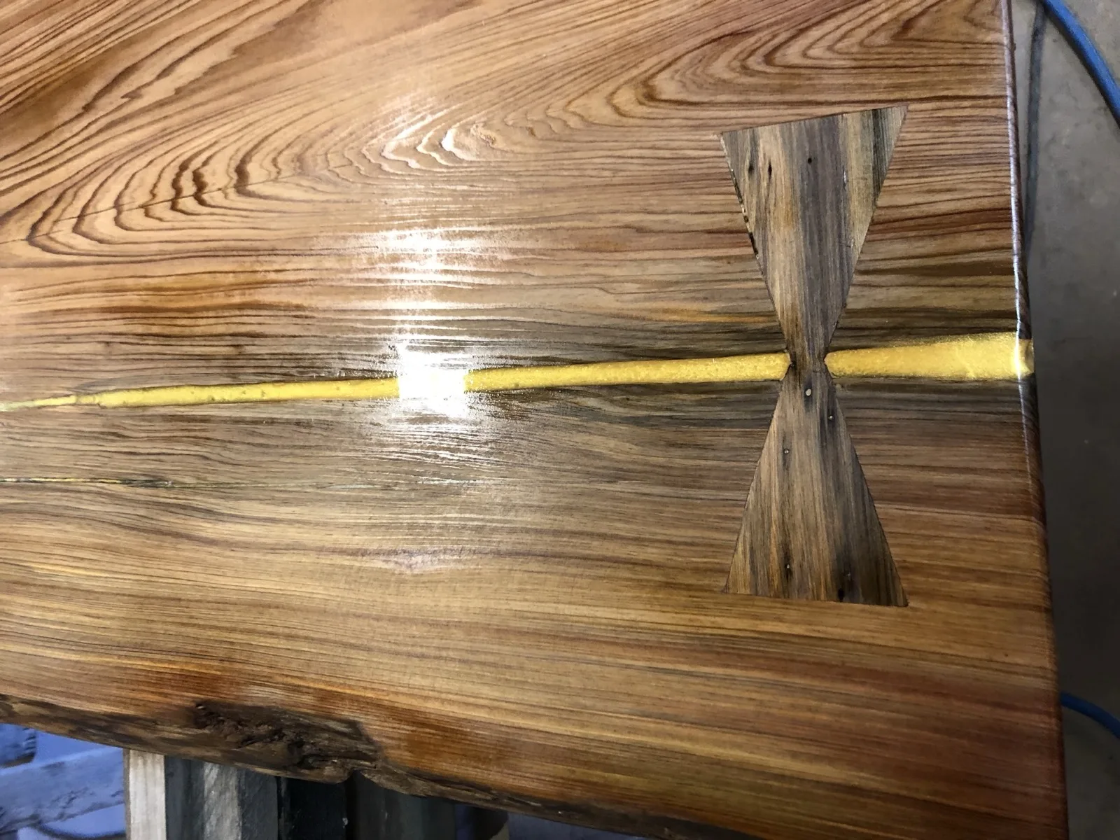 Gold epoxy river with hand-cut butterfly bowtie joints in cypress — craftsmanship detail