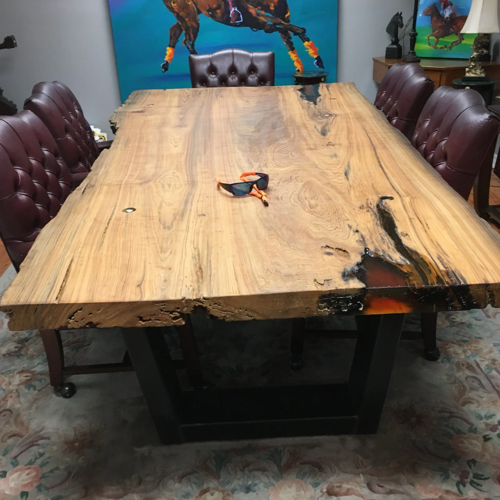 Cypress slab dining table with dark epoxy edges on steel base — leather tufted chairs