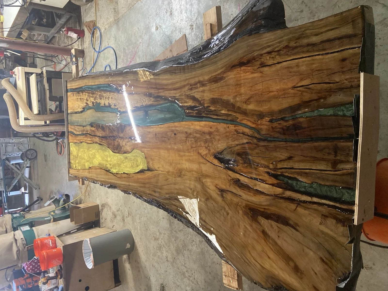 Multi-color epoxy fills — yellow and teal resin in cypress with natural bark edge