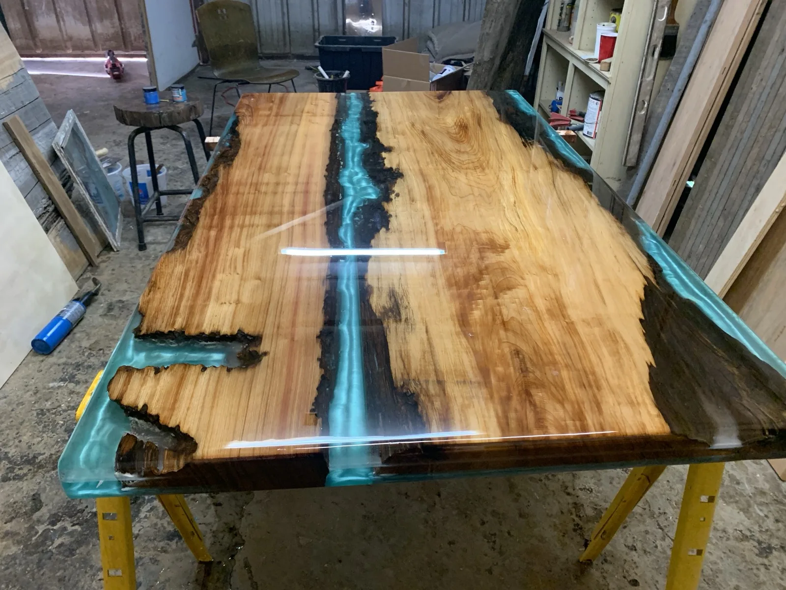 Turquoise epoxy river table — full slab top view on sawhorses in workshop